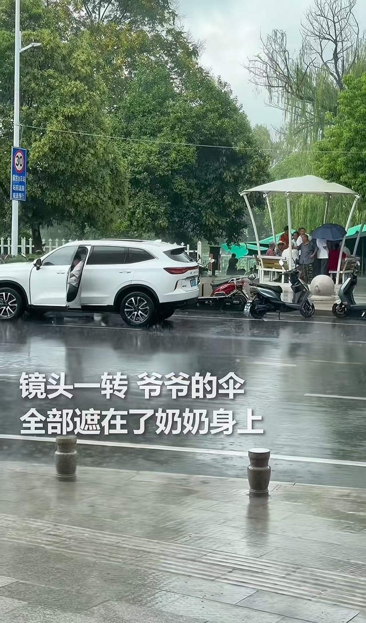 暴雨中的两把“伞”：一把遮风雨，一把暖人心

暴雨突至，街头瞬间被雨水笼罩。一位