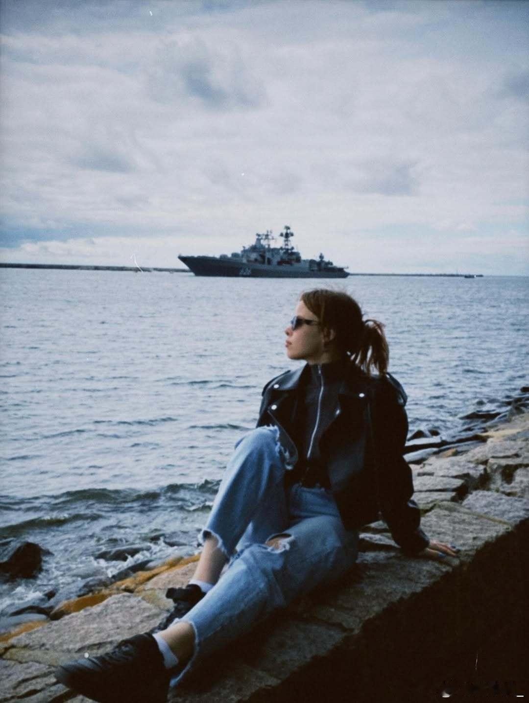 少女在波罗的斯克海边摆pose，背景可见626“库拉科夫海军中将”号大型反潜舰。