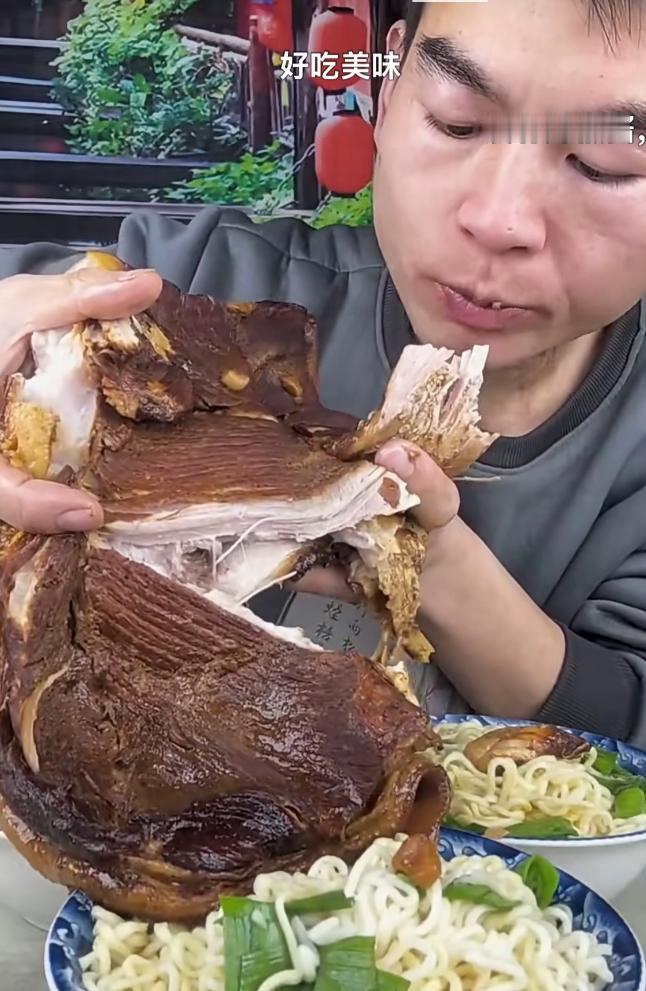 视频里，男子双手抱着一个完整的卤猪肘子，大口撕扯着肥肉和瘦肉，面前还摆着几大碗面