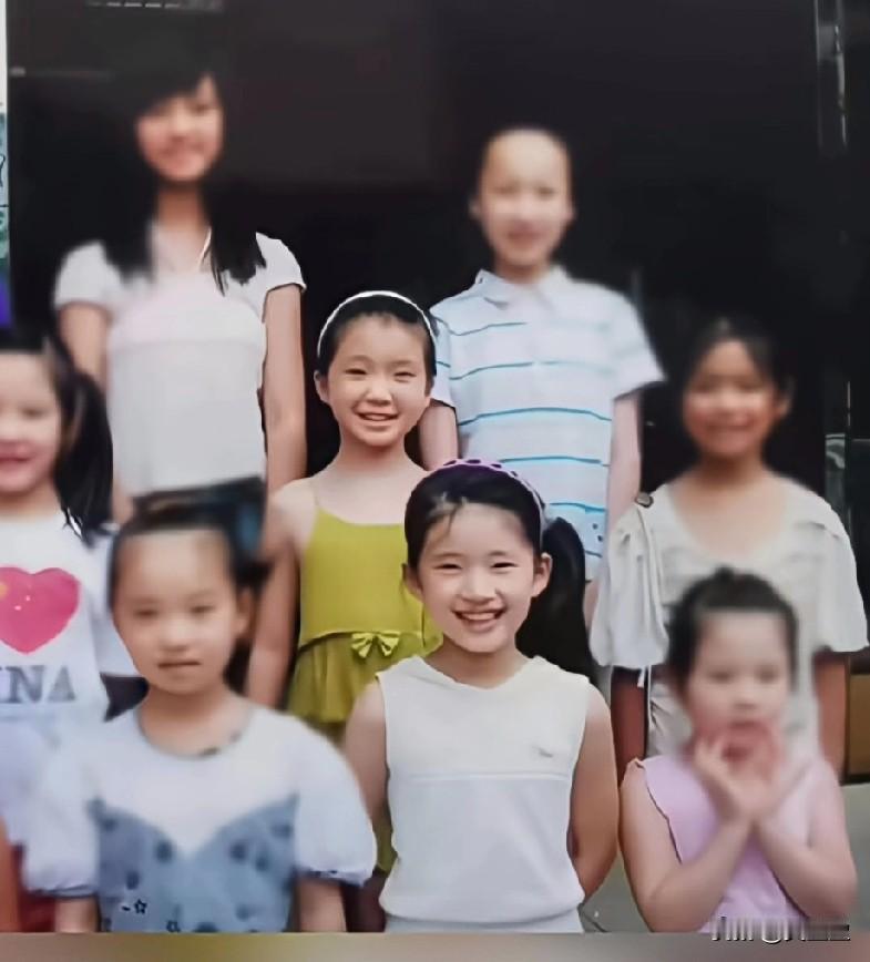 这张童年合影里，穿白色无袖，梳着斜马尾的小女孩笑眼弯弯。谁也不会想到，当年这个软