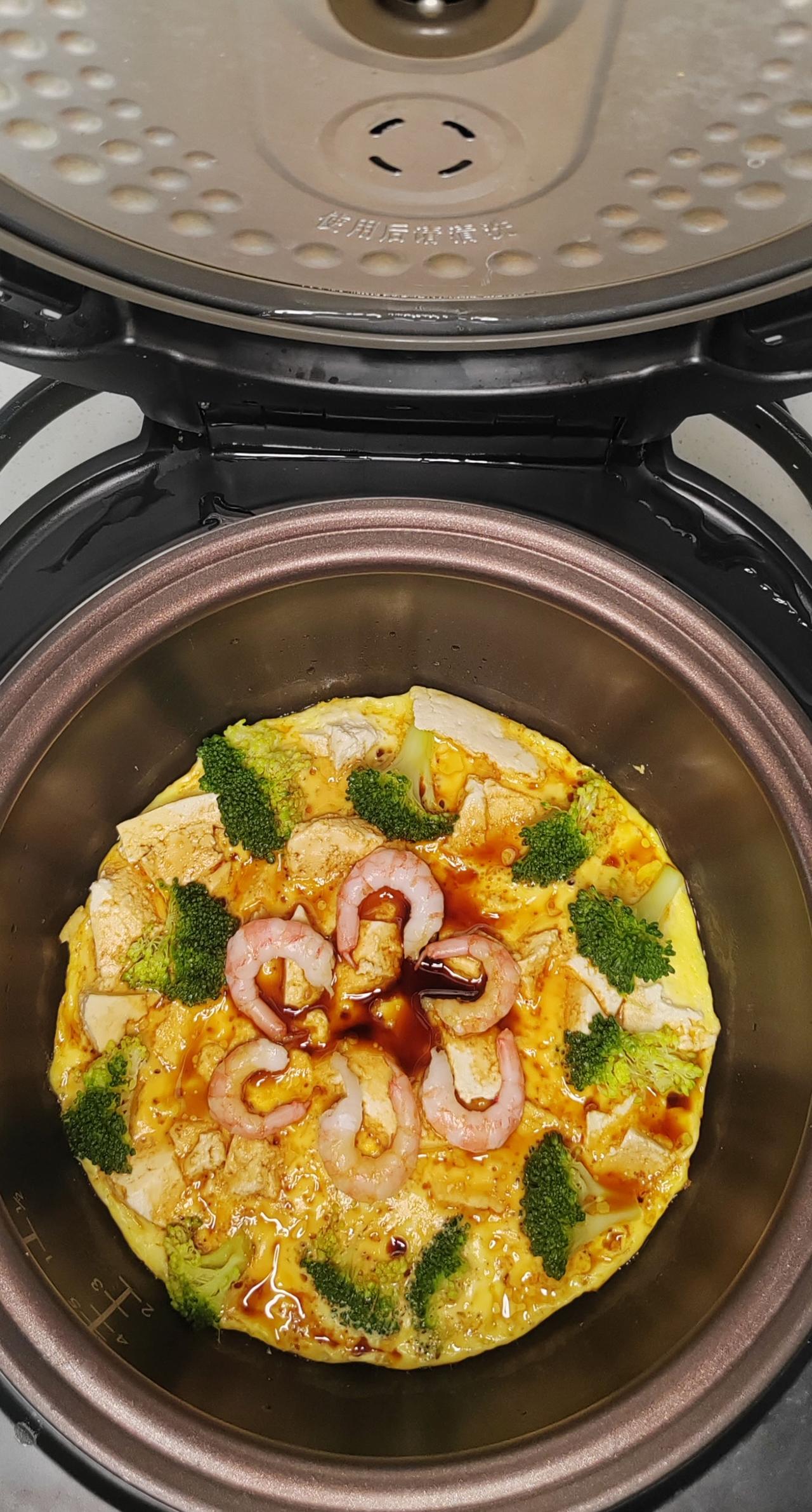操作步骤：盆里刷油，放豆腐碎，两个鸡蛋两勺水，铺西兰花，煮饭键15分钟左右，开盖