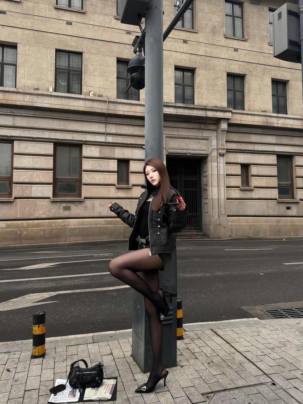 这套穿搭在复古建筑前太有“酷飒辣妹感”了！黑色机车夹克自带凌厉气场，十字架腰带、