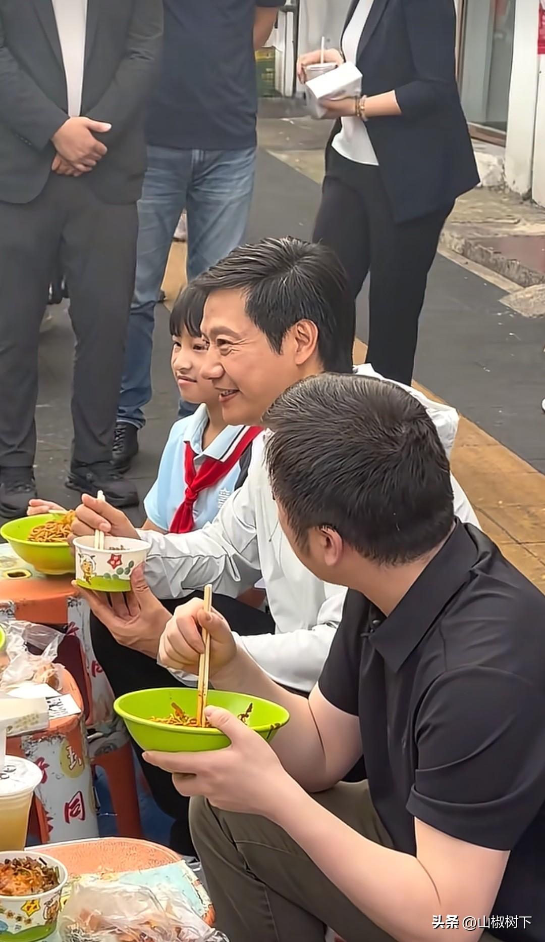 6月15日，雷军在武汉街头吃早餐，周围全是摄像机和手机在拍照，恰巧刚好有一位上学