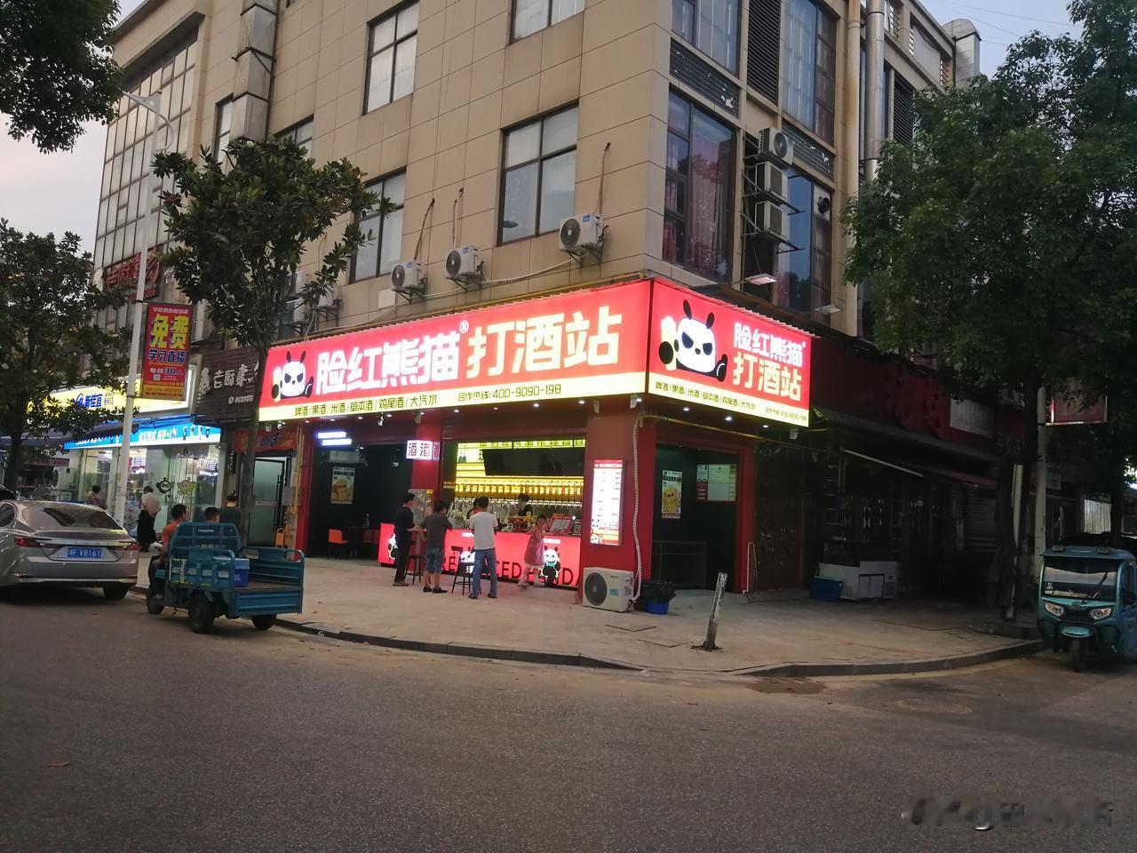 昨天晚上外出散步，竟在城市广场对面发现了这样一家打酒站。
 
这是一家叫“脸红熊