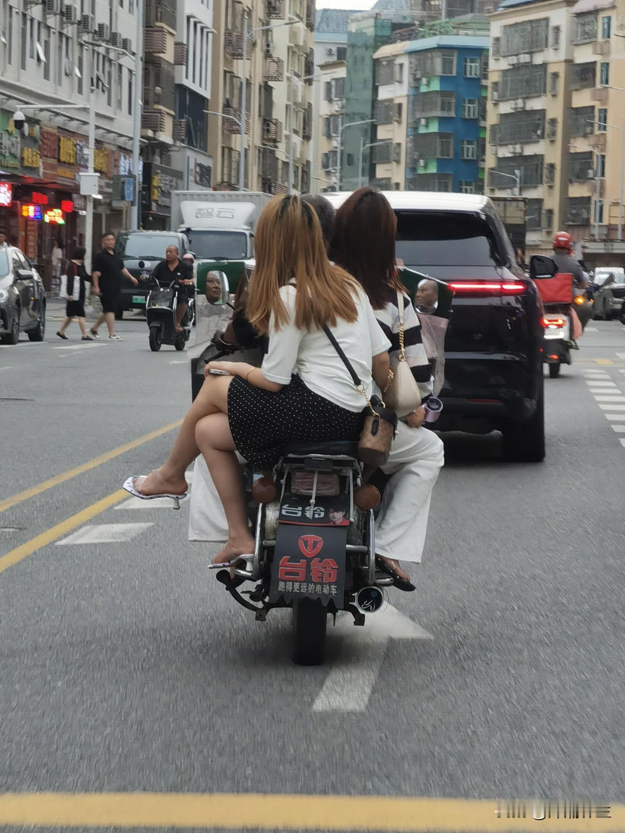 路过深圳某繁忙路段，街头的这一幕让我停下了脚步。画面中，一辆电动车载着两个年轻女