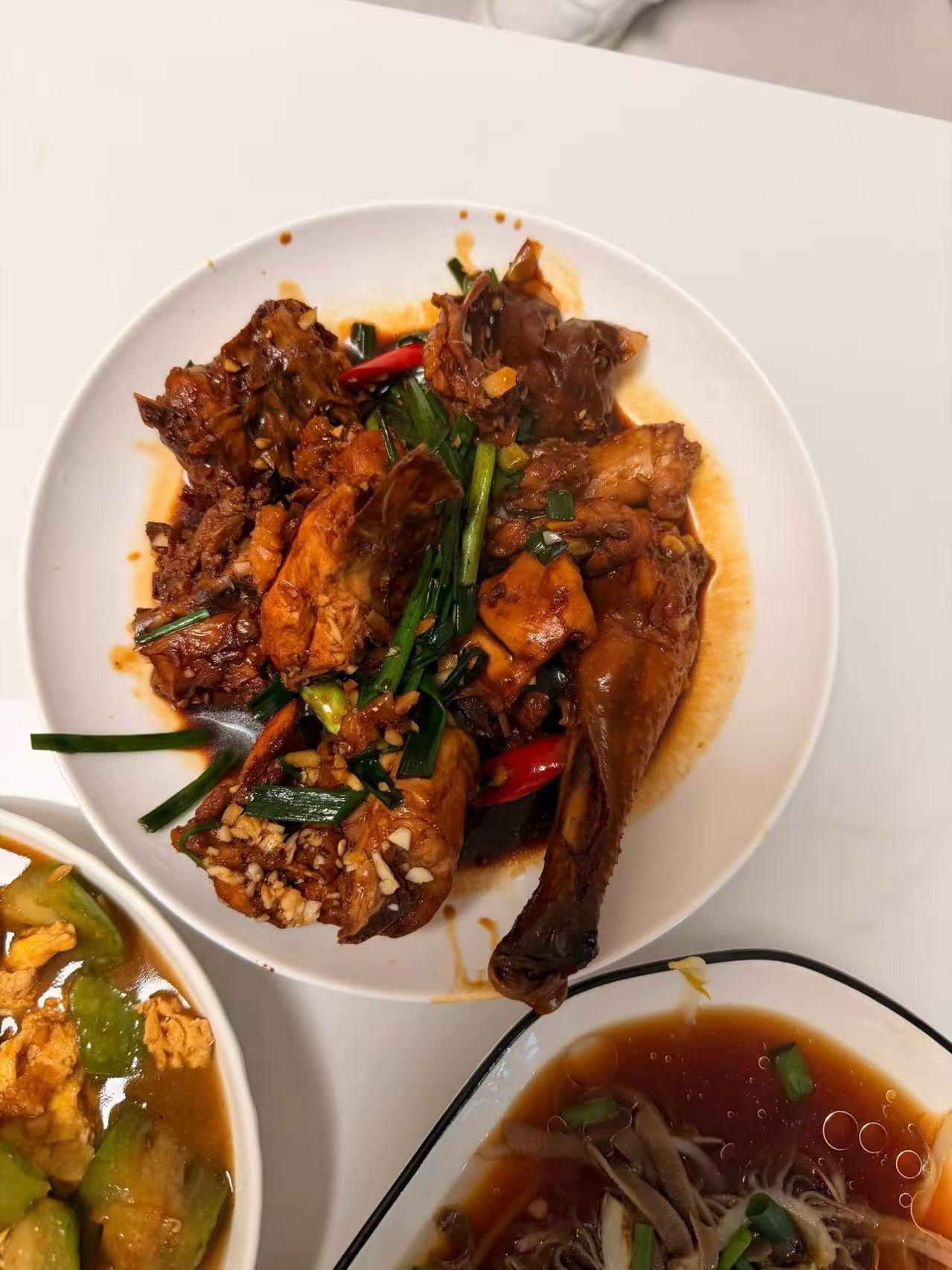 一盘香辣红烧鸡，旁边有汤和炒菜，美味又营养。