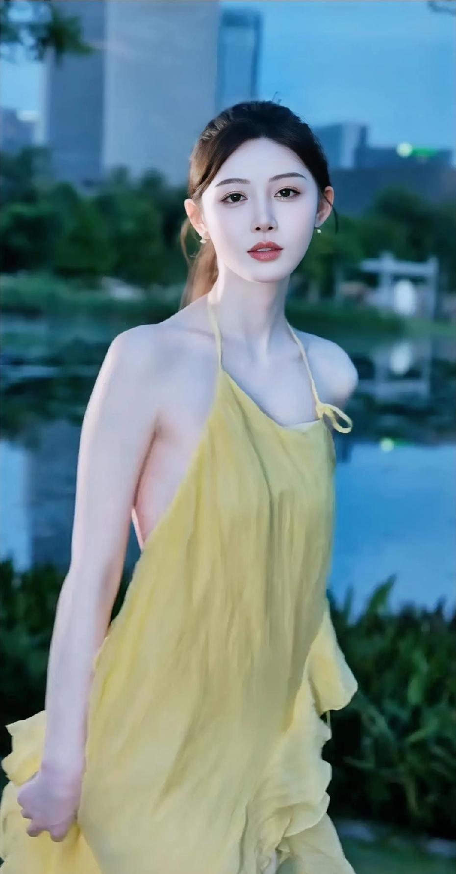 黄衣美人倚水畔，风姿绰约似画中。