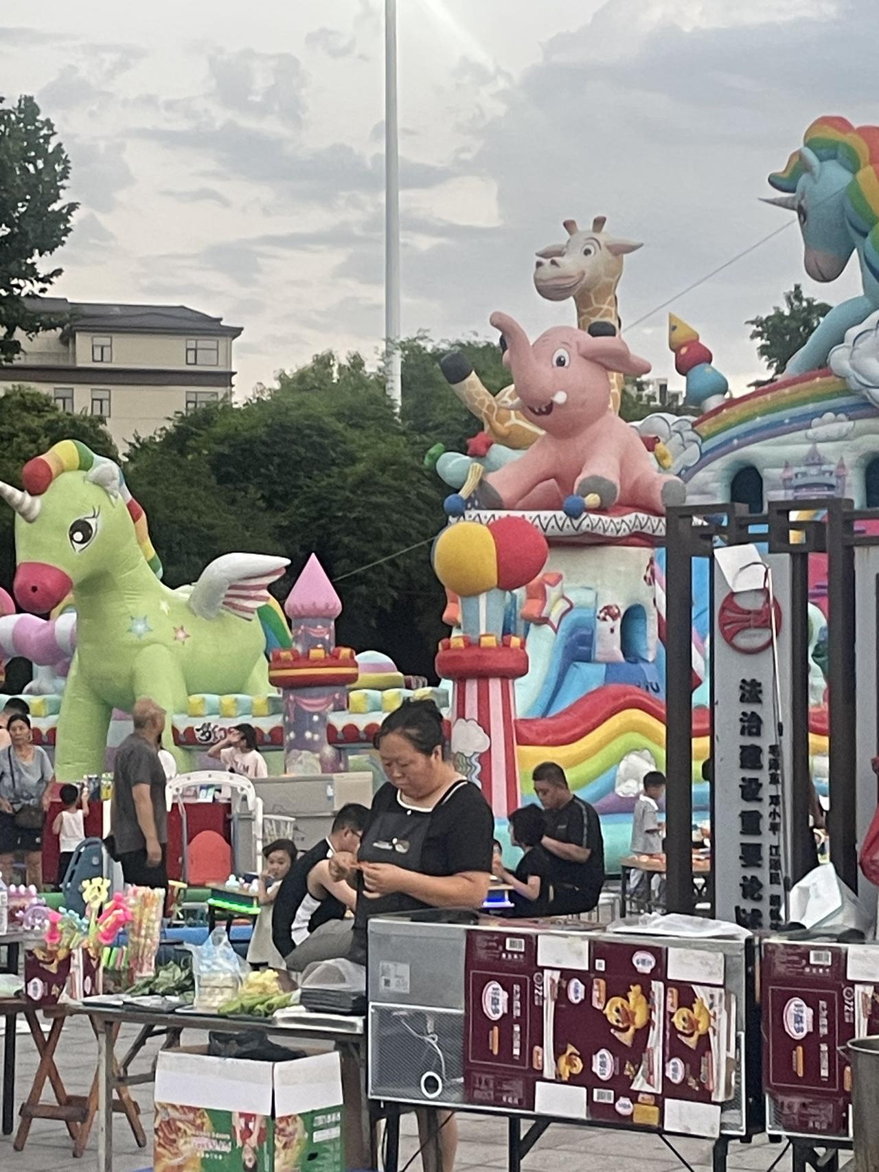 夏日生活打卡季傍晚的广场才是人间最治愈的地方，五颜六色的充气城堡摆满路边，独角兽