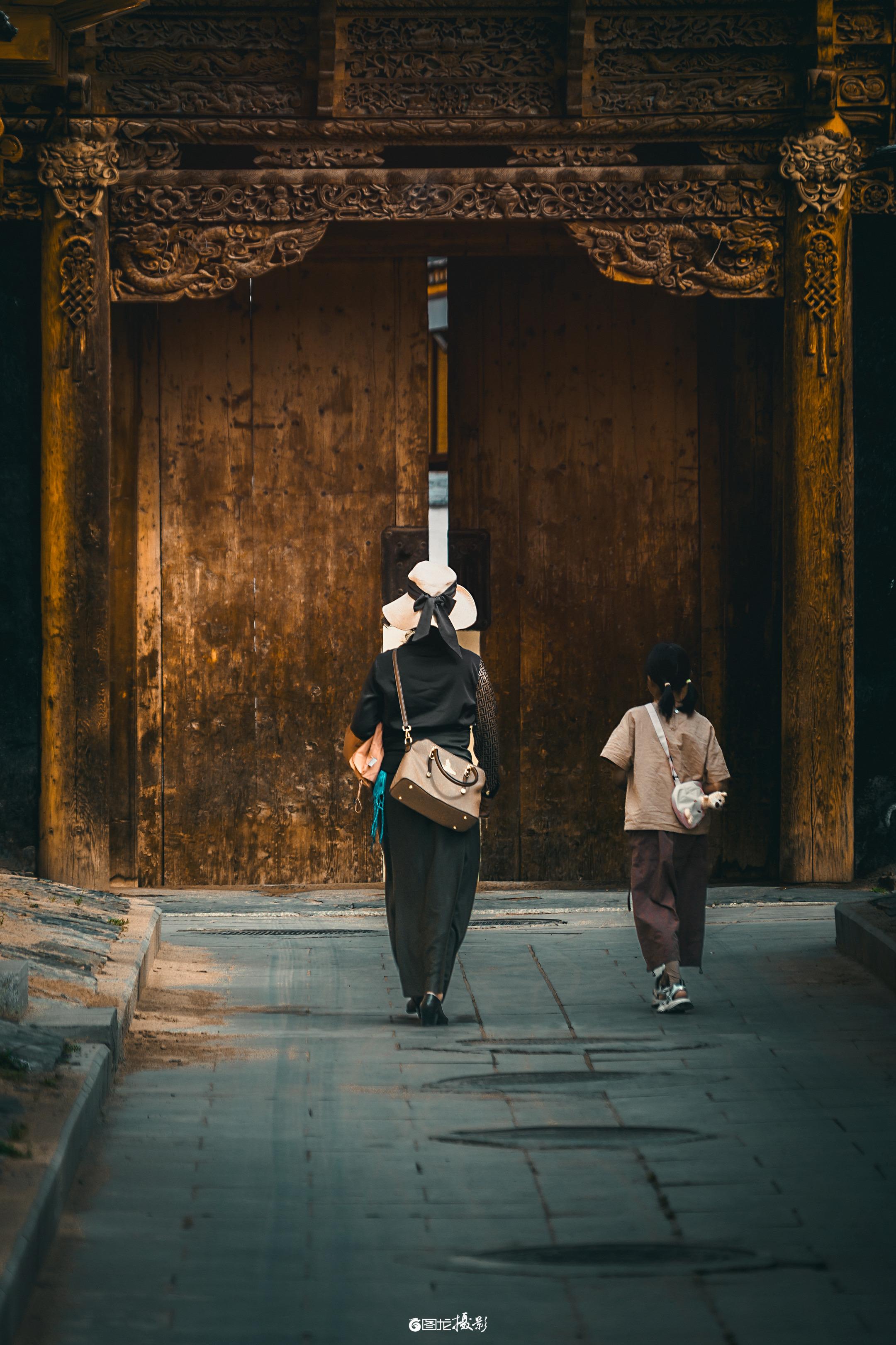 漫步拉卜楞寺，古木雕门镌刻岁月，石板路延伸向信仰深处。母子背影融入庄严...