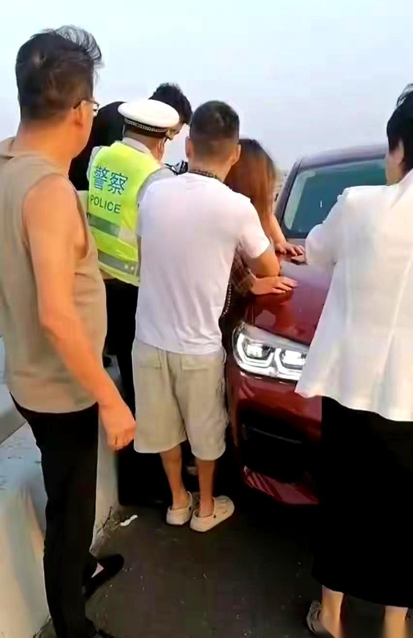 脚底下就是翻滚的海水，胶州湾大桥的风吹得人站都站不稳。
那个女人翻过护栏坐在外侧