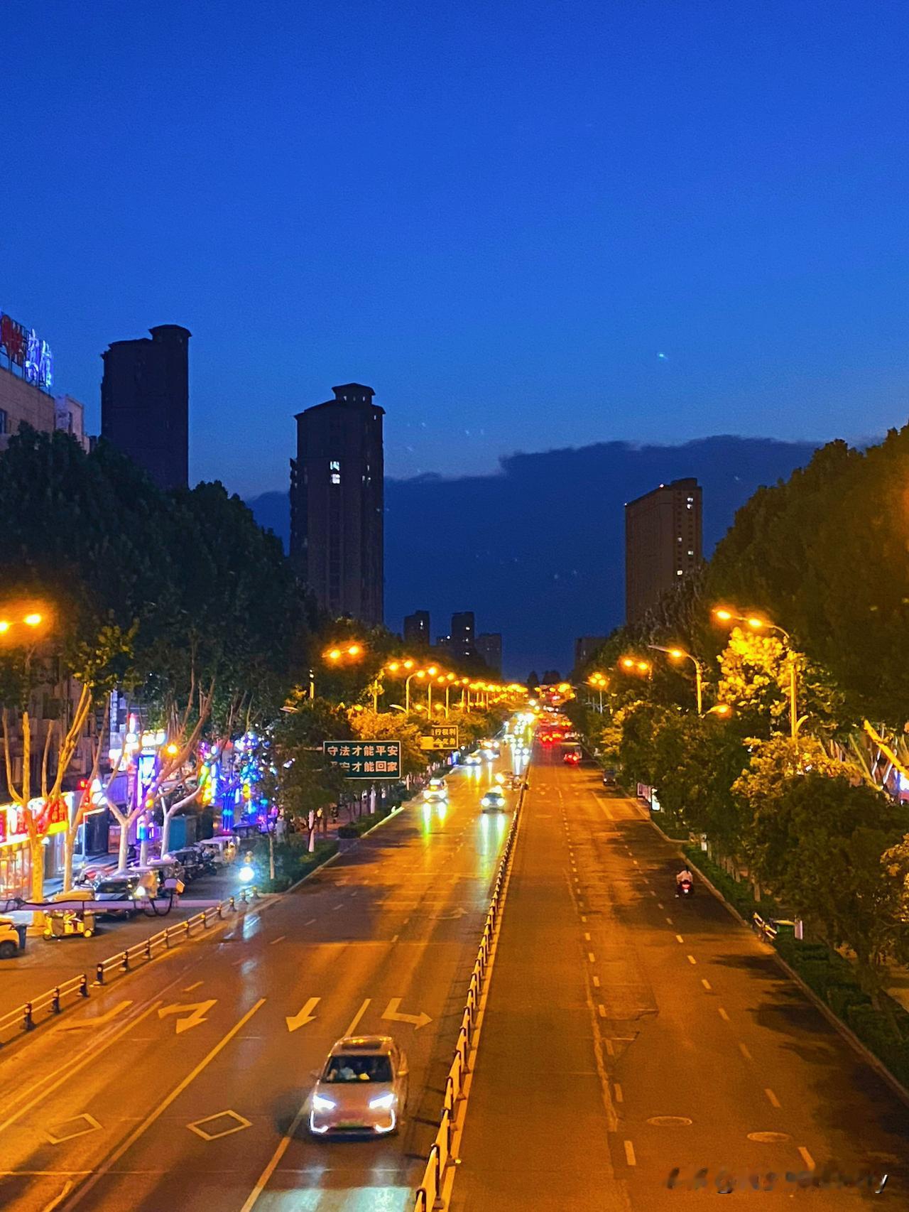 我经常随手拍夜晚街道的照片。有一次在晚上忙完工作出门，那街道灯火通明，像一条发光