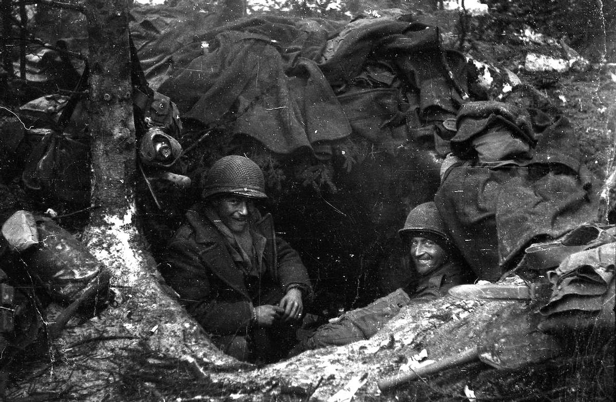 1945年，比利时境内，两名美国士兵正在一处森林隐蔽点休息。
他俩的窝棚是用美军
