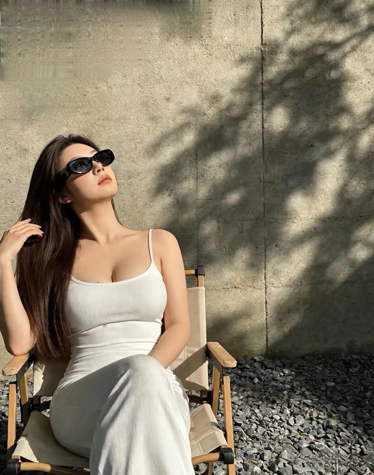 她坐在椅子上，戴着墨镜，看着天空。