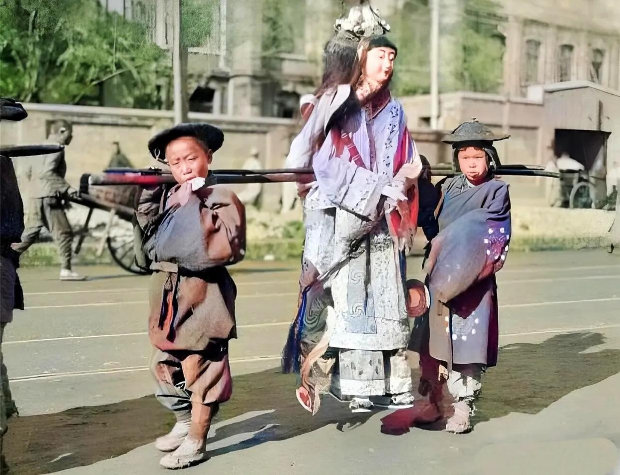 这是民国时期，北京一户大户人家出殡时的照片。照片中，两个小孩子抬着一对纸扎的美女