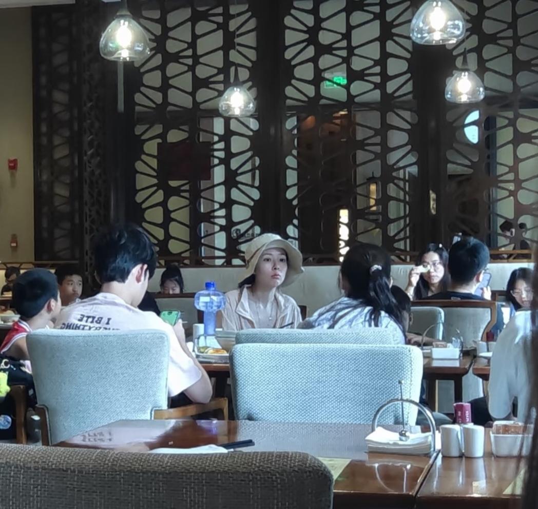 郭碧婷坐在西双版纳一家酒店大厅里吃饭，
戴着帽子，
素颜没有化妆，
萌萌哒的表情