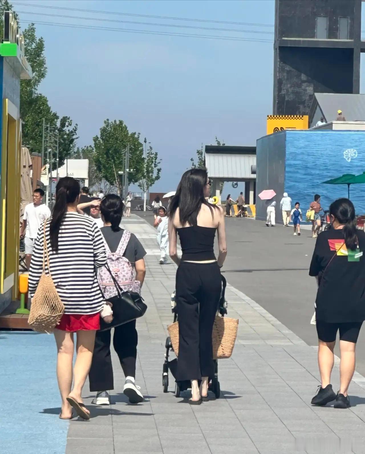 37岁超模何穗带着1岁儿子现身河北旅游，她穿着一身黑色，整个人又高又瘦，皮肤白到