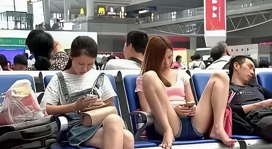 在夏天，一个穿短裤的女孩，在候车厅，两腿之间叉开，完全无所顾忌，旁若无人的刷手机