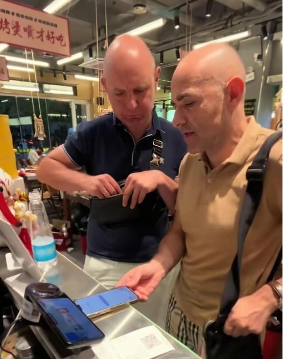 这两个老外在南昌吃烧烤，在前台结账时发现手机无法扫码支付，也没有现金人民币，老板