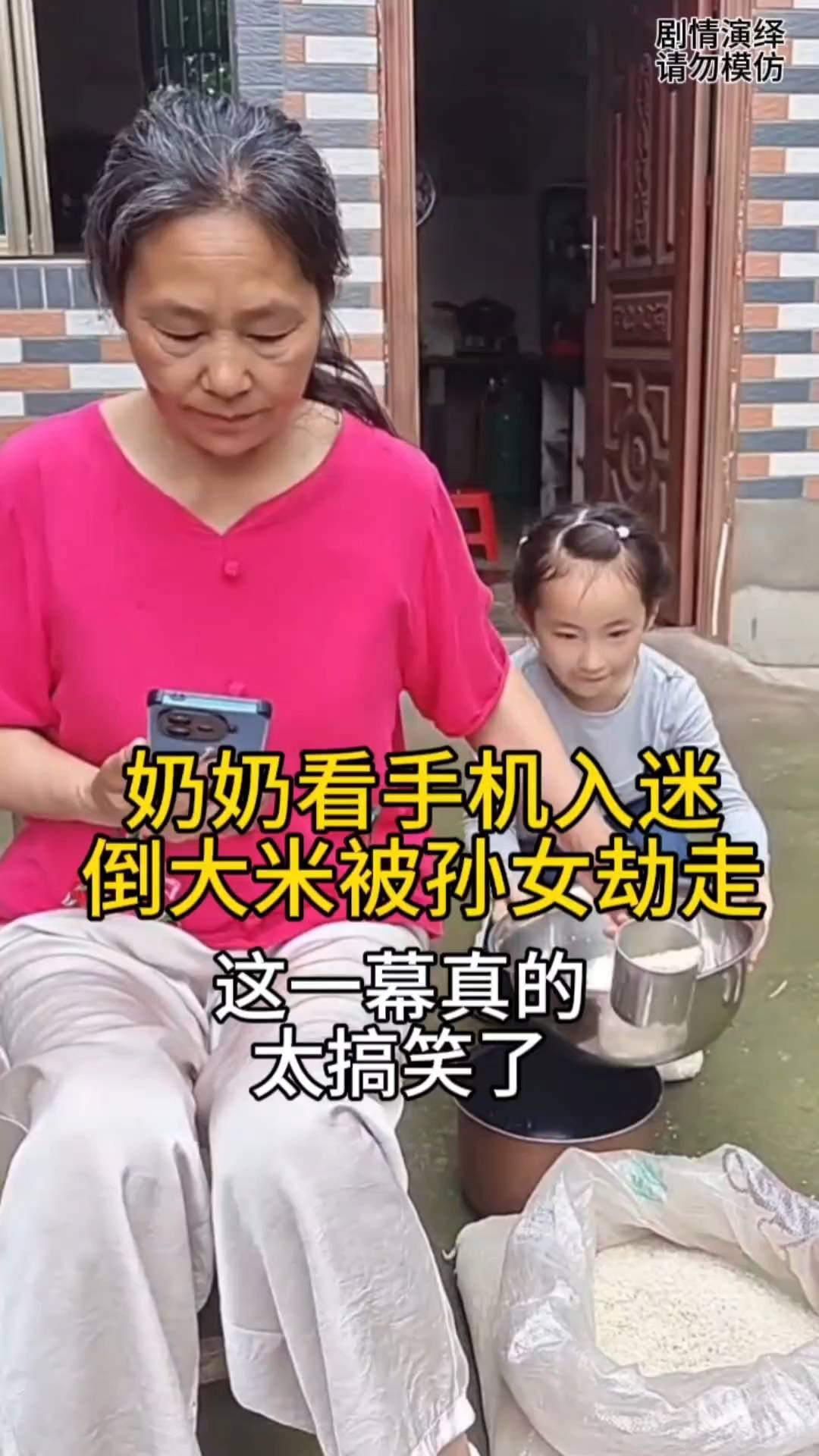奶奶看手机太入迷了，这时她去倒米饭时，孙女看到后赶紧拿盆接，殊不知奶奶此时还不知