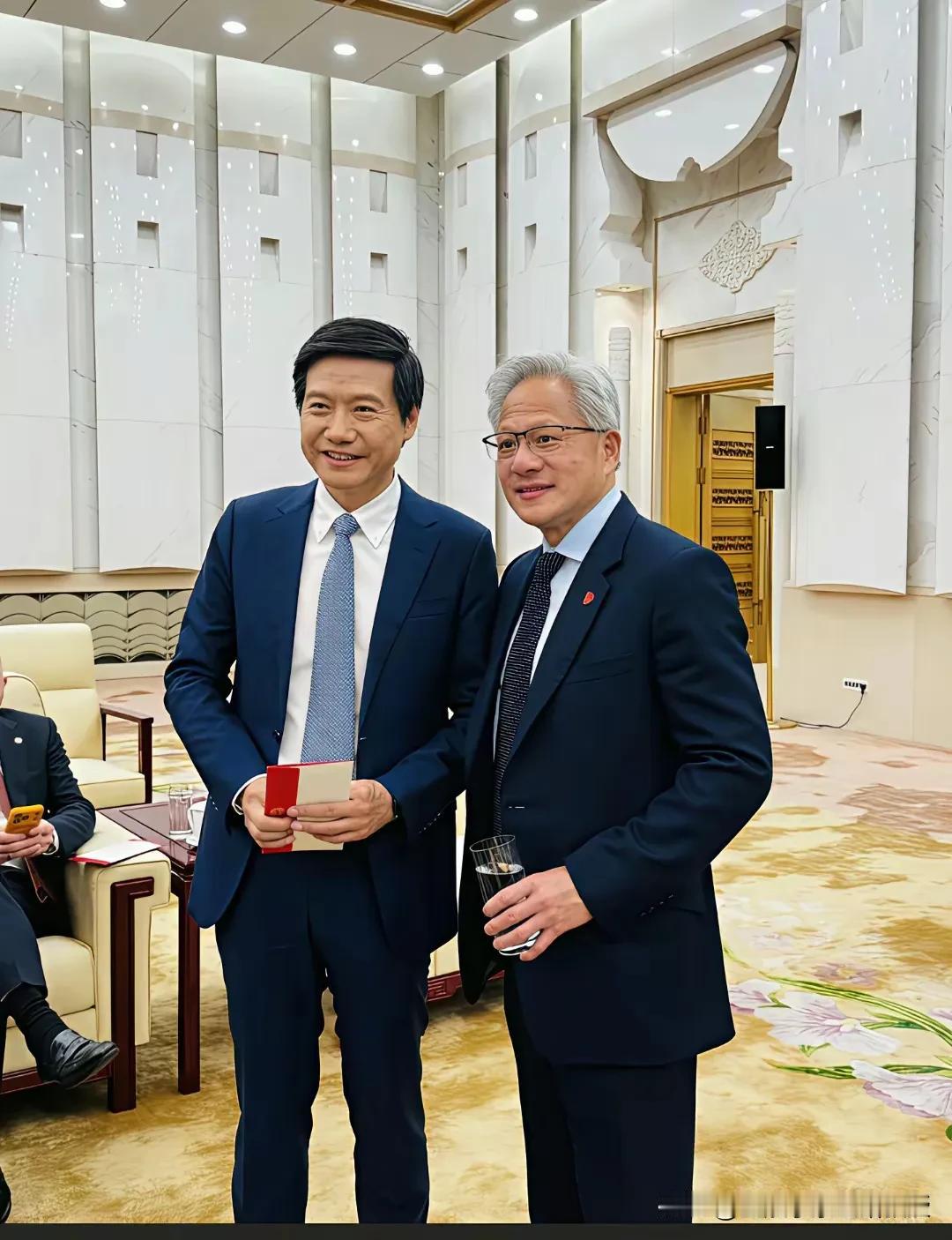 看下图，雷军和黄仁勋这次在人民大会堂见面合影，两人都站着，笑得多灿烂，他们既是朋