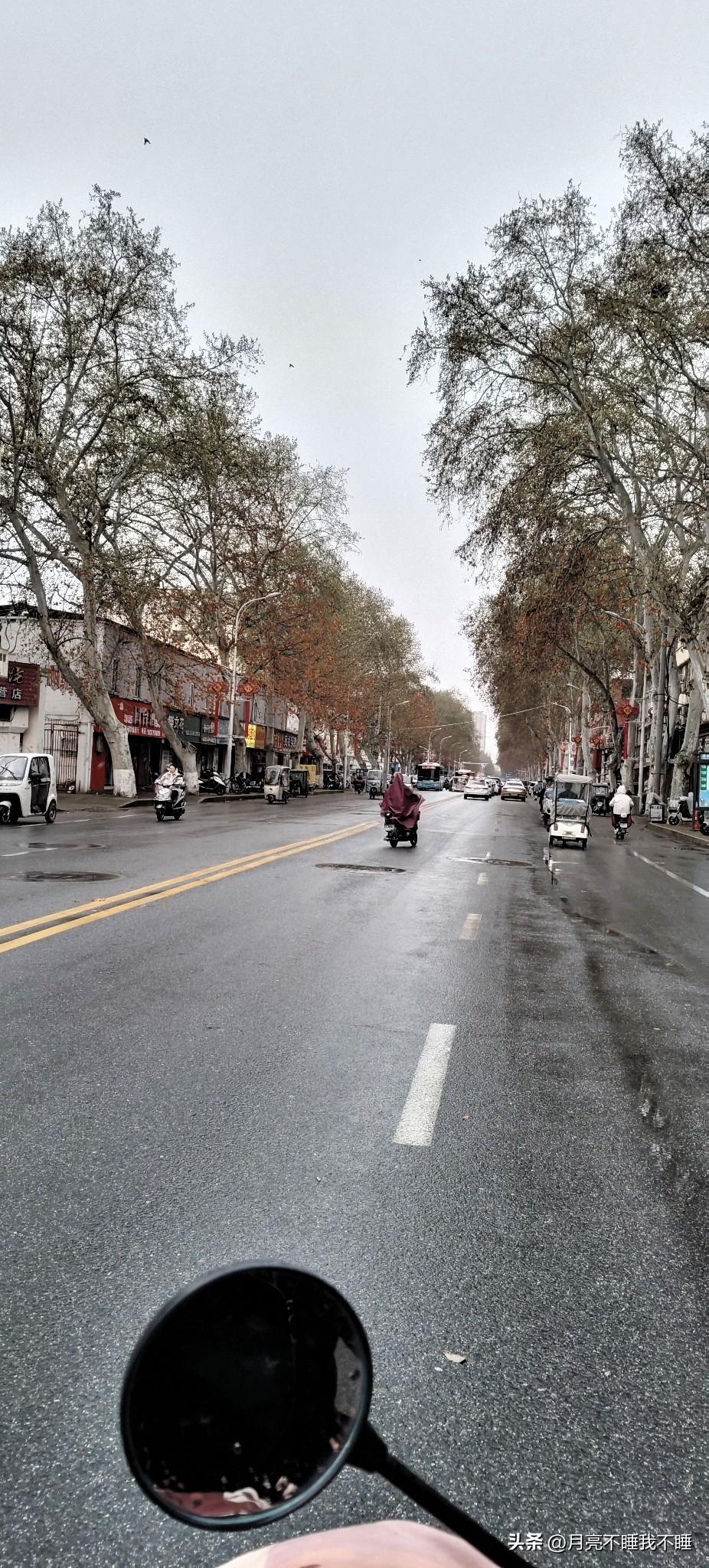 坐在电动车后座，看着后视镜里自己的指尖，路面还带着点湿意，刚下过雨的空气凉丝丝的
