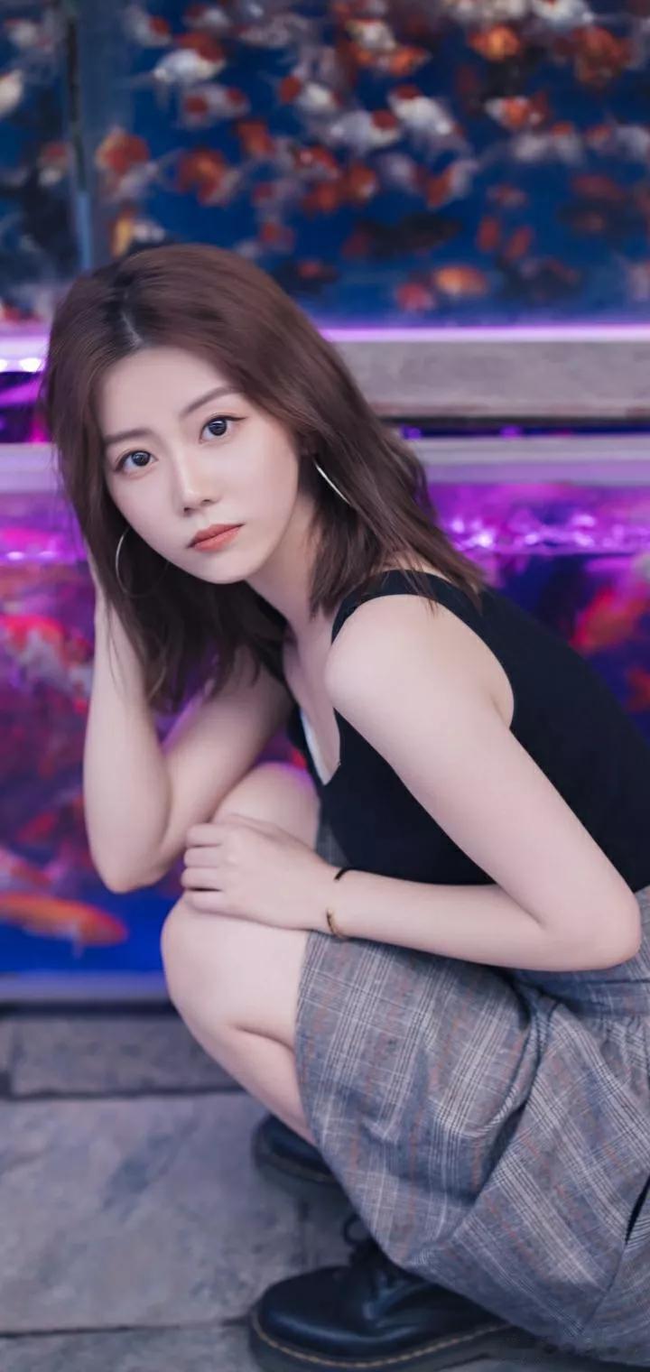 在沉静的鱼池旁，少女轻倚的画面仿佛定格在时光中。
那少女的身姿，透着一种宁静与优