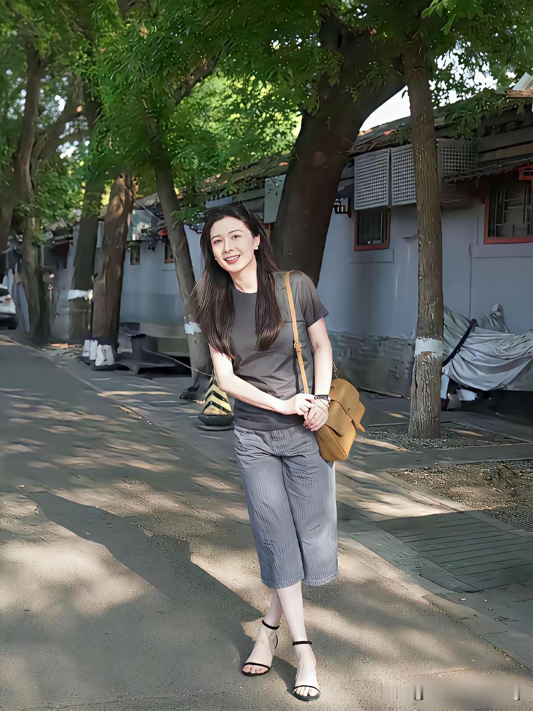 阳光明媚，她微笑着站在树下。