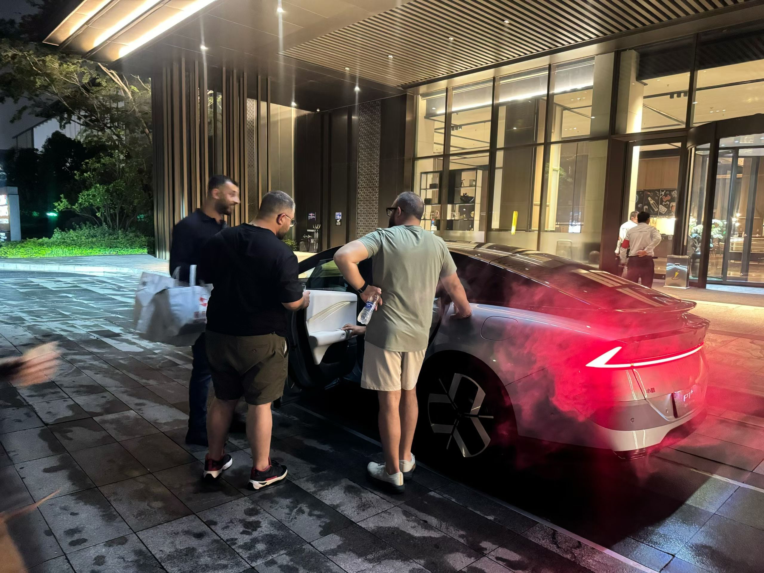 某国的酒店门口…几位外国(巴勒斯坦，我猜的)游客，围着一辆中国电动车(P7+，我