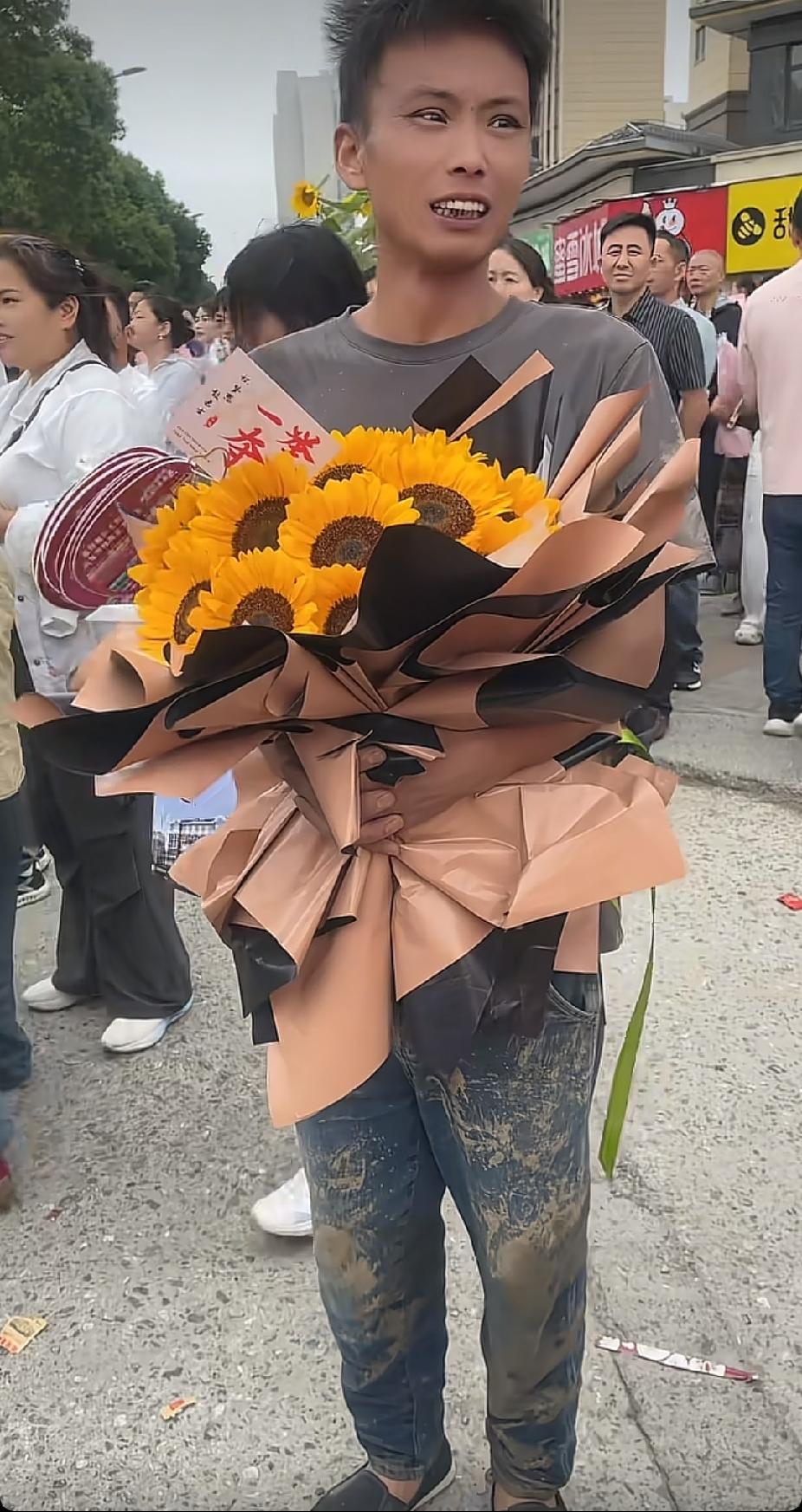 考场门口，一名男子手捧一束向日葵花，看向男子的裤子时，让人瞬间感动泪目了。

今