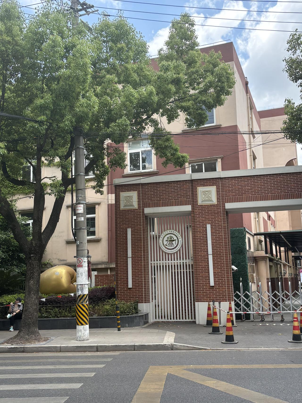 金苹果，是建平的吉祥物；
铁砧、铁锤、书是交大的特征。
哪个学校会在门口集上这两