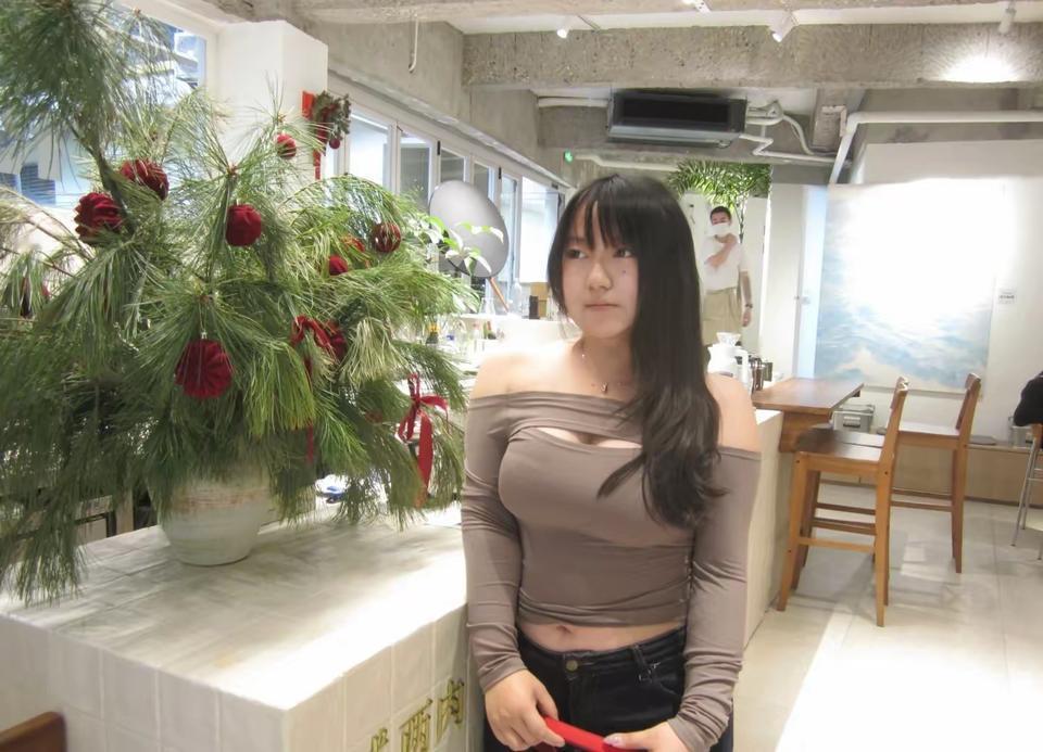 美女站在圣诞树旁，手拿红色物品。能否发表一句今生感悟