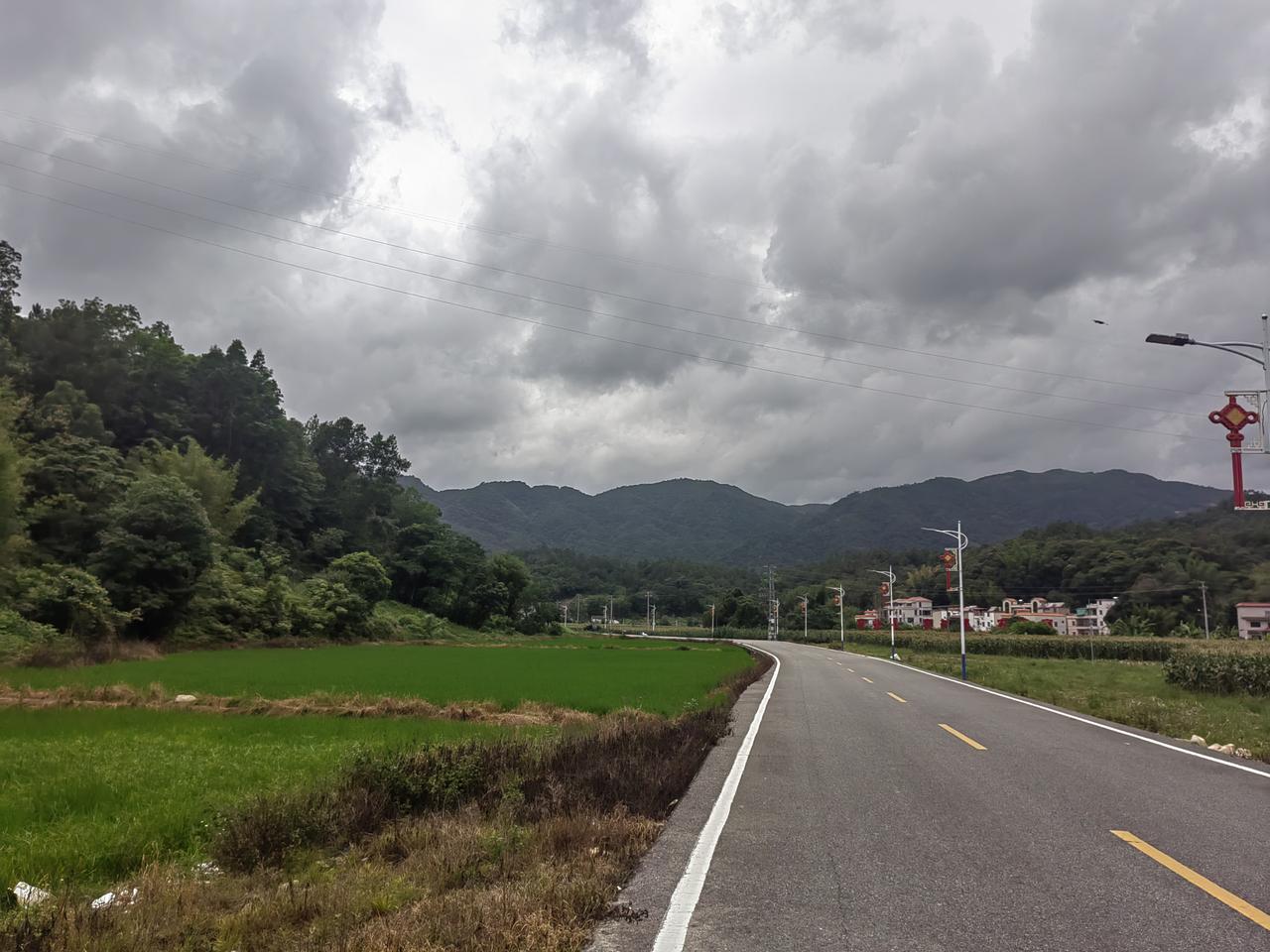 一条乡间小路，绿油油的田野，远山连绵。