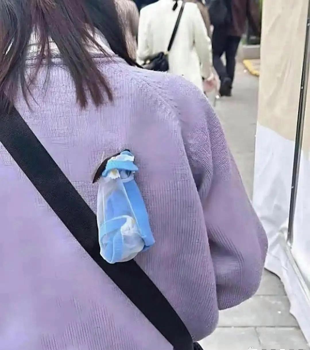 跟在这位女士身后走了好久，越看越别扭。
一个小东西牢牢别在后背上，她自己完全没有