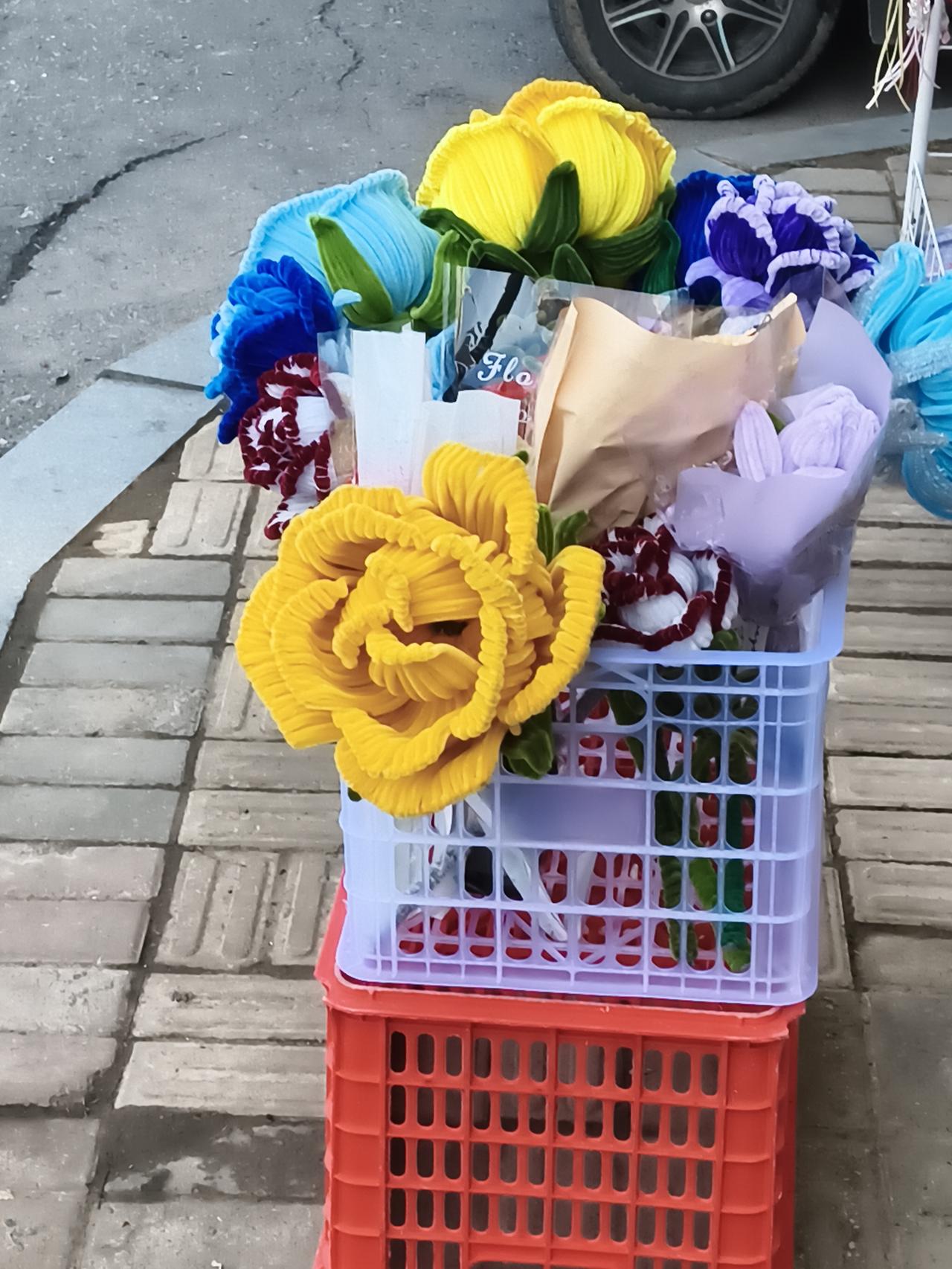 它们没有鲜花的娇弱，却多了一份持久的精致。在略显冷清的街边，这抹亮色格外动人，仿