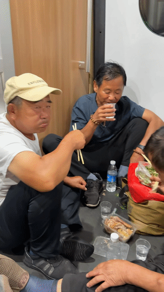 火车上有几个大叔聚在一起坐在地上吃饭。
看他们谈笑风生，一边喝酒一边聊天。
真是