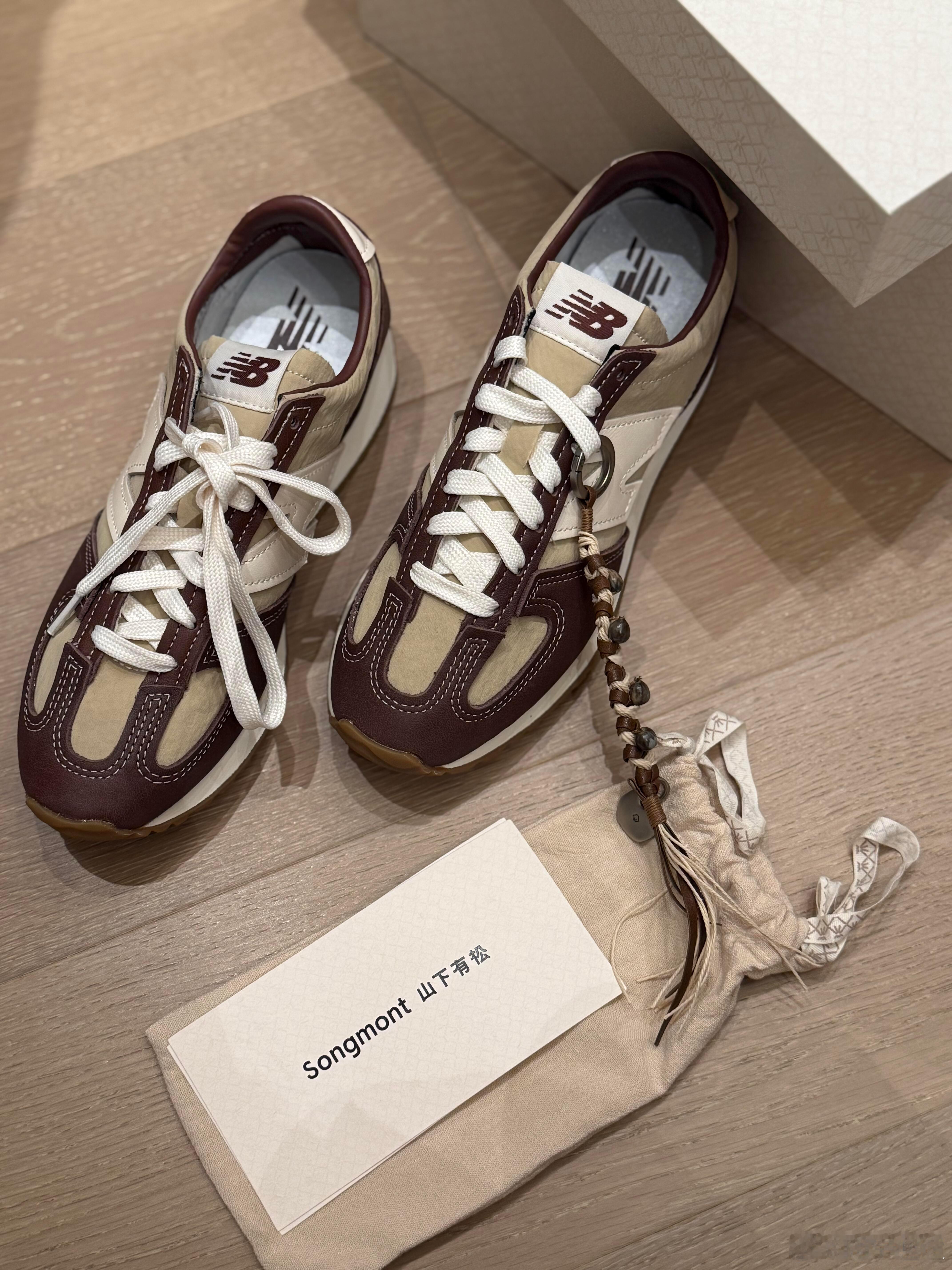 这双New Balance复古跑鞋以其优雅的酒红与米白配色脱颖而出。鞋面采用酒红