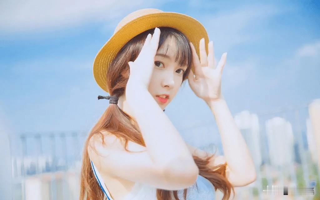 阳光明媚，女孩在桌边微笑。阳光明媚，她戴着草帽摆姿势。自然微笑写真 唯美