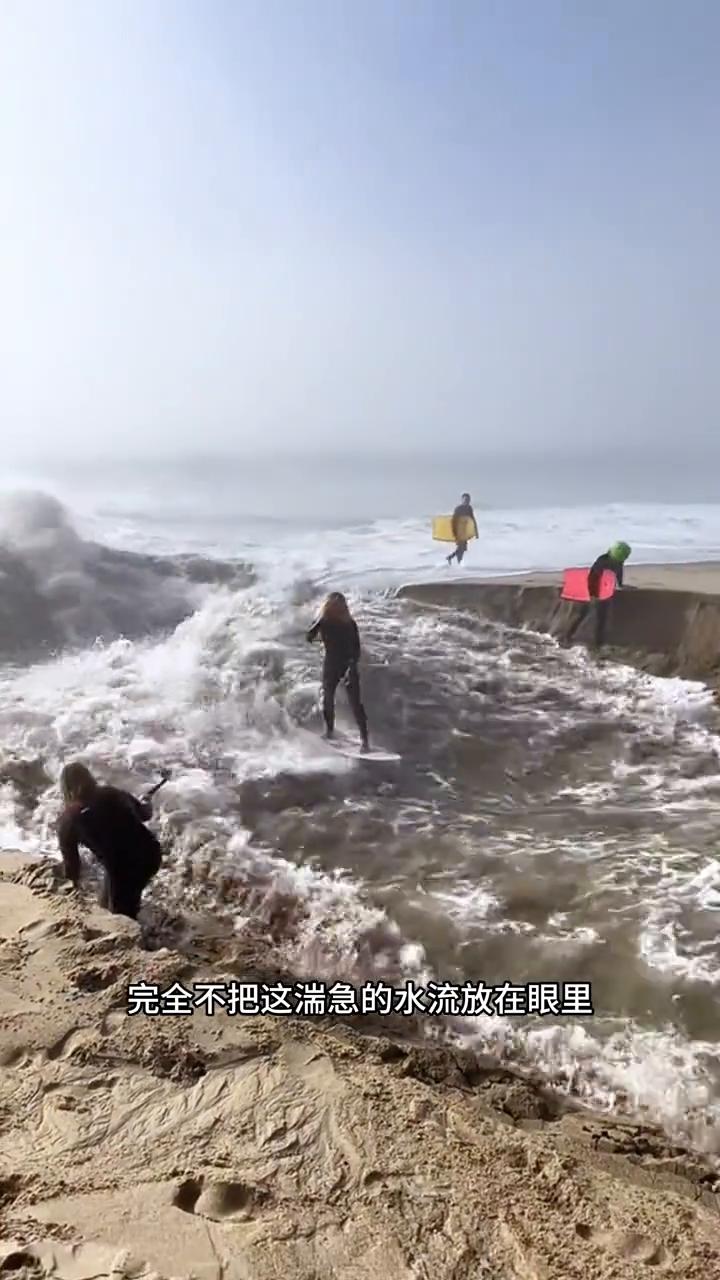 注意看，这已经是十分凶猛且湍急的入海口浪层，可是男子却还是拿了一个冲浪板就直接跳
