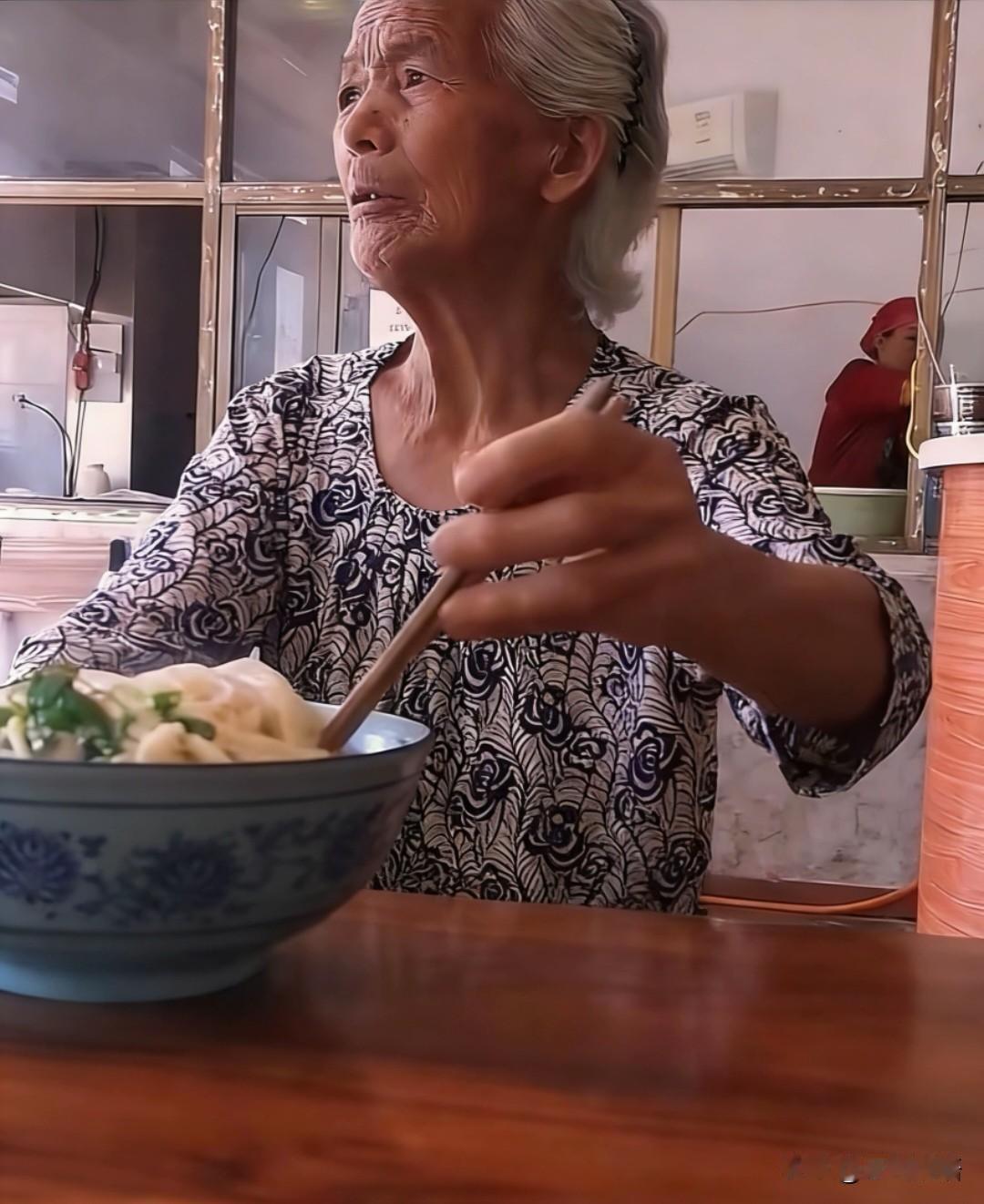 一老人挑着碗里的牛肉面一口不吃，眼睛一直盯着饭馆门外。原来他的老伴在对面台阶上坐