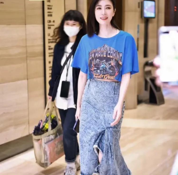 贾静雯穿着一件非常时尚的克莱因蓝T恤，这是一款超短的款式。这件宽松的露腹T恤衫展
