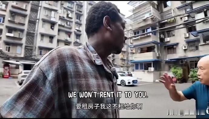 一个老外，举着手机在小区里边走边拍，结果被一群摇着扇子的大妈给“堵”在了门口——