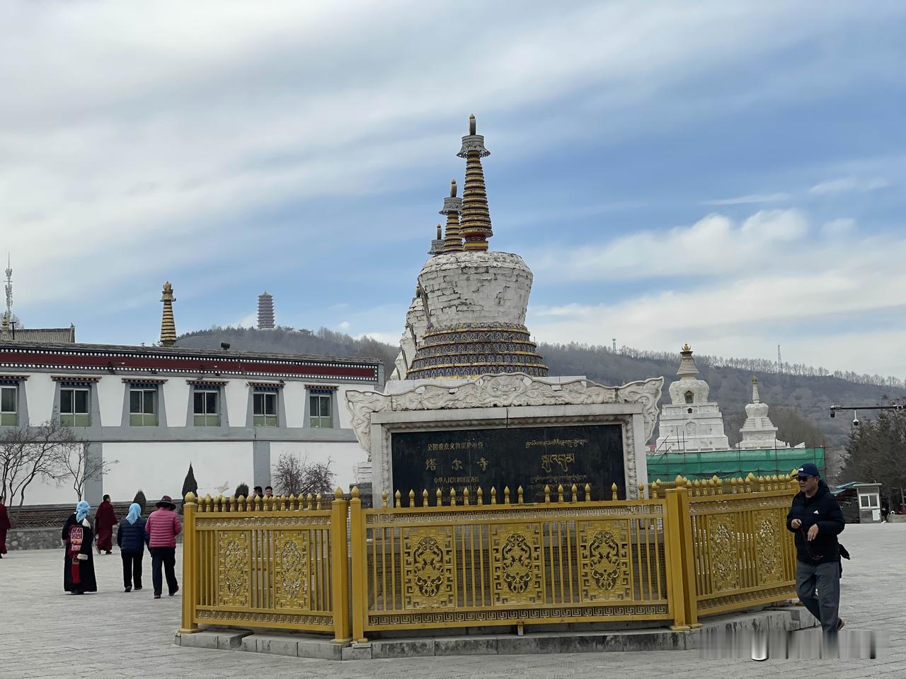 踏入塔尔寺，金顶红墙在香火氤氲中静立，八宝如意塔旁的转经筒被信徒缓缓拨动，诵经声