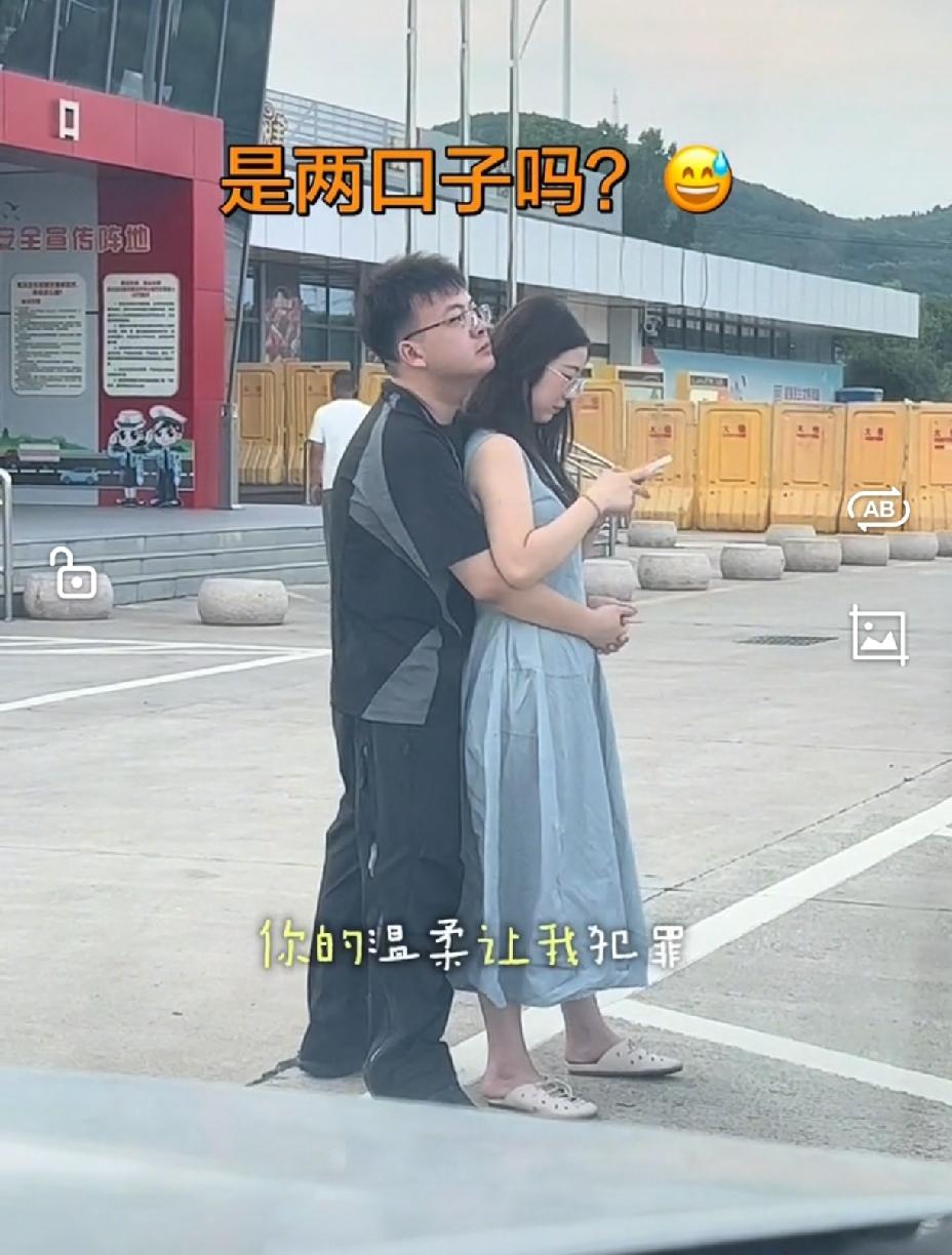 男人的行为表情，一看就是非常的爱着怀里的女人，在大路边都把女人抱得紧紧的。