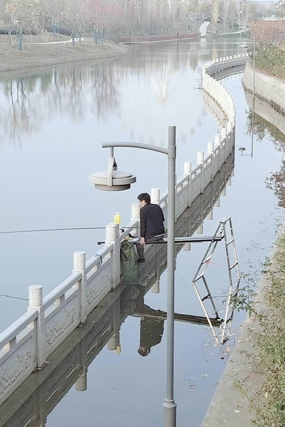 为了钓好鱼都是绞尽脑汁呀，这哥们用人字梯搭块板子，架在护栏上就悠哉地钓上了，感觉