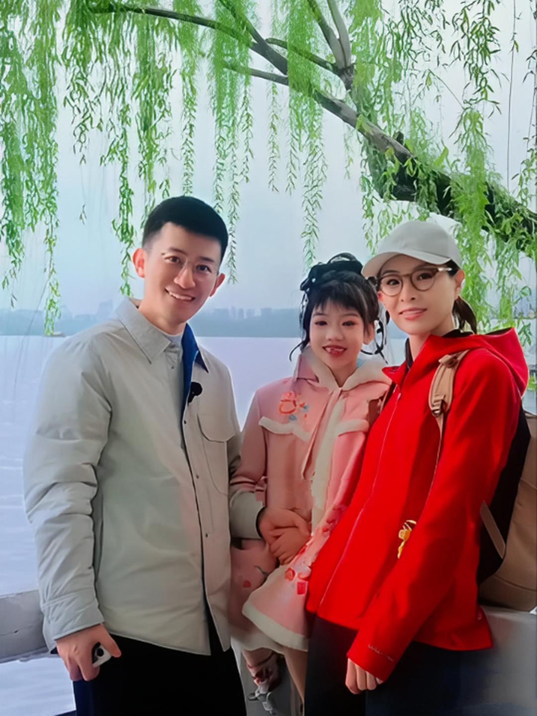 跳水奥运冠军吴敏霞和老公张效诚还有女儿西西在公园游玩，吴敏霞一身大红色外套，白色