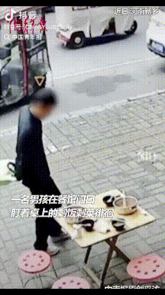 近日，河南新乡，一男孩路过一家餐馆门口时不走了，眼晴一直盯着桌上的剩饭剩菜看，随