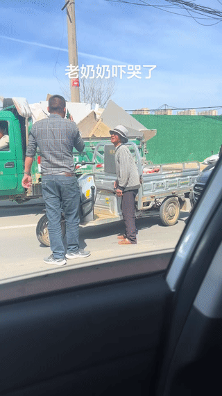 老奶奶的电动三轮车不慎撞到了一辆私家车？
车主一边打电话报警一边拦着老奶奶不让她