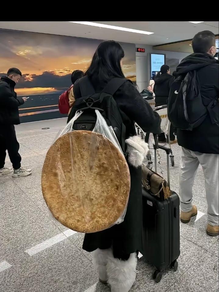 一女子在机场等着过安检，万万没想到女子的背上竟然背了一个硕大无比的馕，远看这馕占