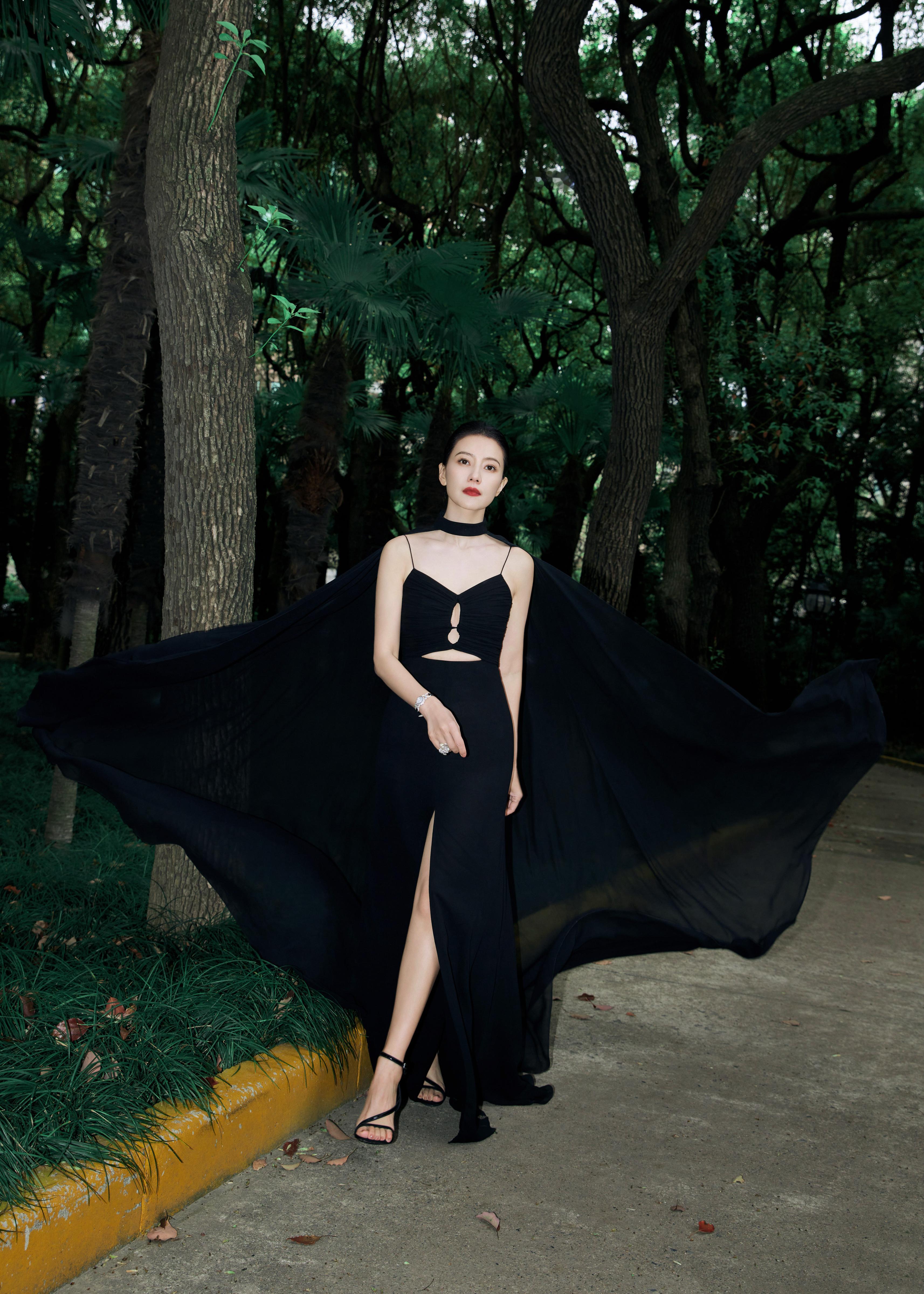 这组造型以一袭曳地黑裙与飘逸斗篷，在葱郁林间织就出神秘又高贵的氛围感。极简剪裁勾