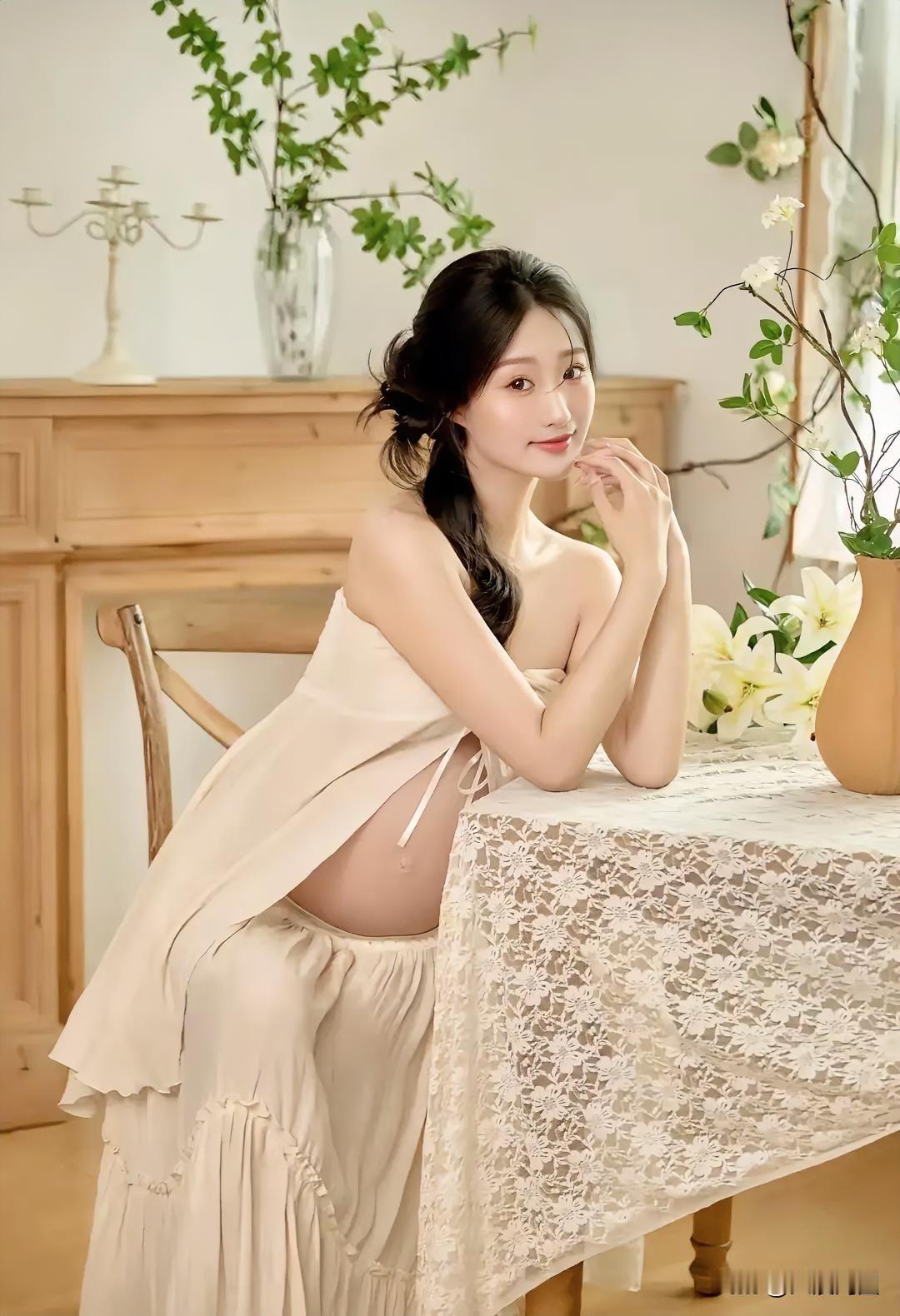 看到一位美女孕妇坐在桌边对着镜头微笑，画面太治愈了。就像有个漂亮的黑发孕妇坐在黑